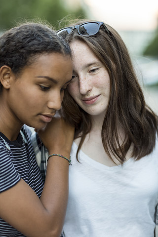 Two teenage girls close together outdoors stock photo