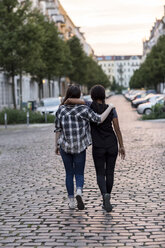 Zwei Teenager-Mädchen gehen Arm in Arm auf einer Straße - OJF000115