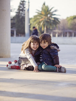 Spanien, Girona, lächelnder kleiner Junge und Mädchen sitzen nebeneinander auf dem Boden - XCF000057