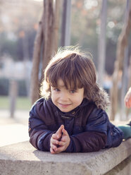 Portrait of smiling little boy lying on a bench - XCF000058