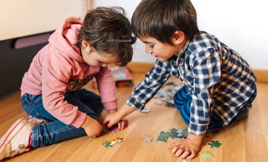 Junge und Mädchen puzzeln zusammen auf dem Boden - MGOF001418