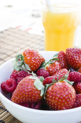 Erdbeeren und Himbeeren in einer Schüssel und ein Glas Orangensaft - ABZF000200