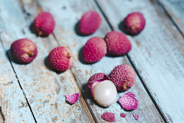 Ganze und geschälte Lychee auf hellblauem Holz - MAEF011258