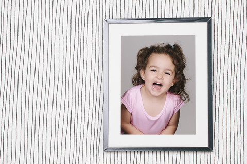 Gerahmte Fotografie eines kleinen Mädchens auf gestreifter Tapete, lizenzfreies Stockfoto