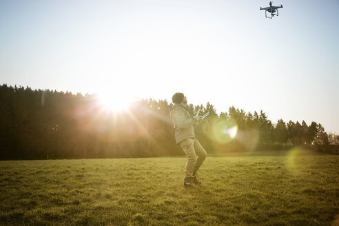 Mann auf einer Wiese fliegende Drohne - REAF000024