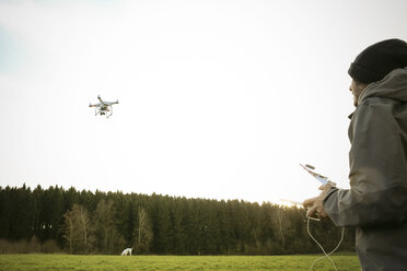 Mann auf einer Wiese fliegende Drohne - REAF000031