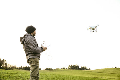 Mann auf einer Wiese fliegende Drohne - REAF000032