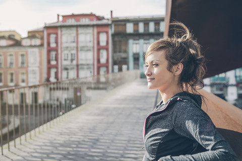 Porträt einer sportlichen Frau mittleren Alters auf einer Brücke stehend, lizenzfreies Stockfoto