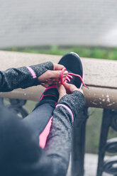 Woman tying shoelaces of pink and black sneakers - DAPF000034