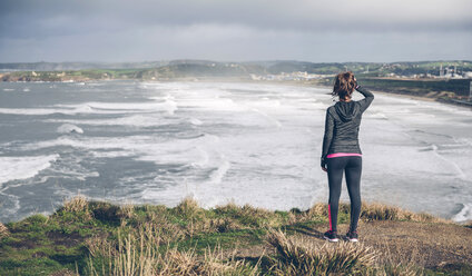 Sportliche erwachsene Frau auf einer Klippe mit Blick aufs Meer - DAPF000041