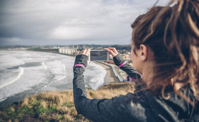 Sportliche Frau im mittleren Erwachsenenalter, die ein Foto mit ihrem Smartphone macht - DAPF000043