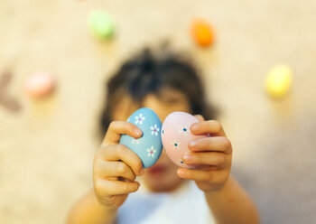Girl's hands holding two painted Easter eggs - MGOF001424