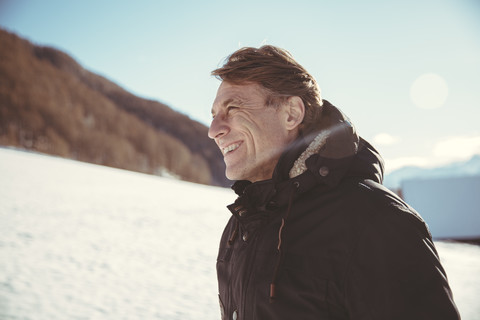 Italien, Vinschgau, Slingia, lächelnder reifer Mann in Winterlandschaft stehend, lizenzfreies Stockfoto