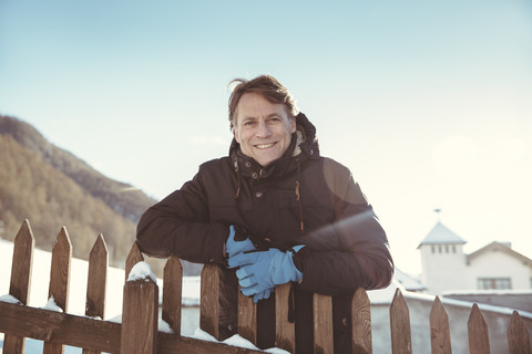 Italien, Vinschgau, Slingia, Porträt eines lächelnden reifen Mannes am Zaun stehend, lizenzfreies Stockfoto