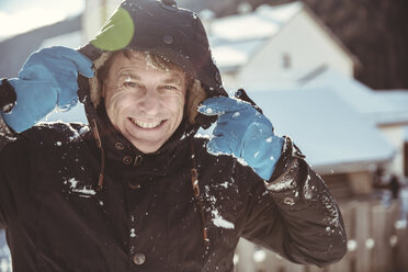 Italy, Val Venosta, Slingia, portrait of smiling mature man holding on to his snowy hood - MFF002705