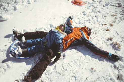 Italien, Vinschgau, Slingia, glücklicher Vater und Sohn liegen im Schnee - MFF002706