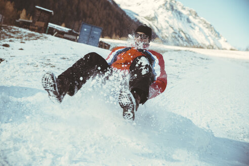 Italien, Vinschgau, Slingia, Mann fährt mit dem Schlitten einen verschneiten Hügel hinunter - MFF002714