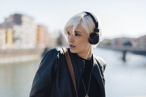 Italien, Verona, Porträt einer blonden Frau, die mit Kopfhörern Musik hört - GIOF000751