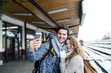 Glückliches junges Paar auf dem Bahnsteig, das ein Selfie macht - HAPF000204