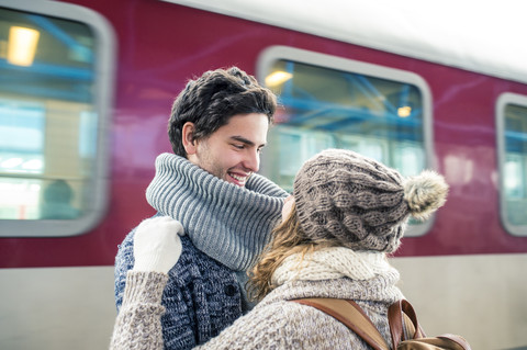 Glückliches junges Paar vor einem Zug, lizenzfreies Stockfoto