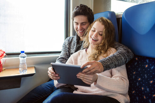 Lächelndes junges Paar im Zugwaggon mit digitalem Tablet - HAPF000225