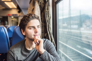 Young man in train car looking out of window - HAPF000230