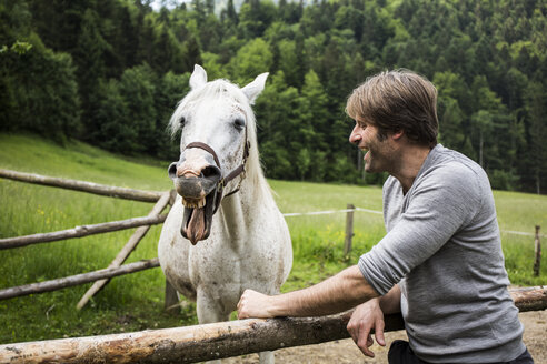 Deutschland, Bayern, Bad Tölz, Mann mit Pferd am Zaun - TKF000428