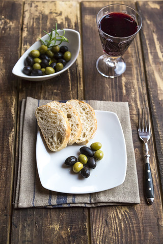 Mit Baguettescheiben und Oliven und einem Glas Rotwein anrichten, lizenzfreies Stockfoto