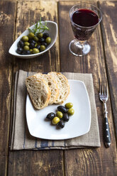 Plate with baguette slices and olives and a glass of red wine - SARF002542