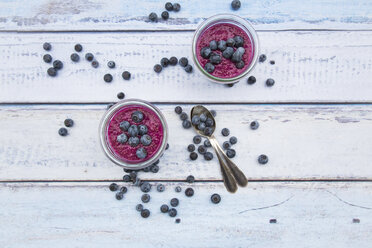 Two glasses of chia blueberry pudding and two tea spoons on wood - LVF004518