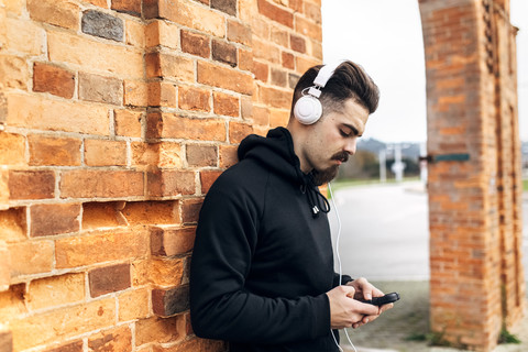 Porträt eines jungen Mannes, der mit Kopfhörern Musik hört, lizenzfreies Stockfoto