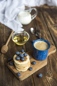 Ein Stapel Mini-Pfannkuchen, Blaubeeren, eine Schale Honig, Milch und eine Tasse Kaffee - SARF002549