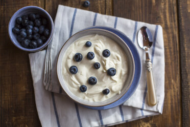 Joghurt mit Blaubeeren in Schale auf Holz - SARF002555