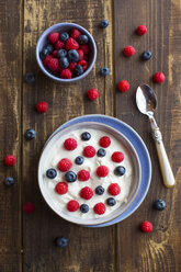 Joghurt mit Heidelbeeren und Himbeeren in einer Schale auf Holz - SARF002557