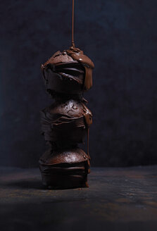 Flüssige Schokolade tropft auf einen Stapel von drei Schokoladenmuffins - KSWF001737