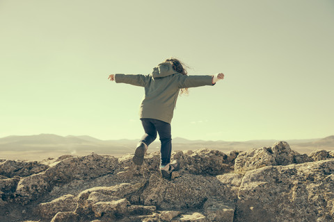 Spain, Consuegra, back view of little girl balancing on rocks in the mountains stock photo