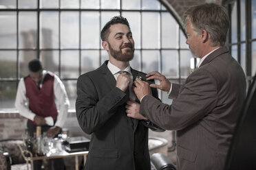 Best man helping groom getting ready before the wedding - ZEF008402