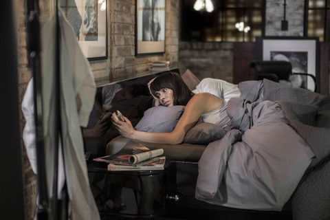 Woman sleepless in bed looking at alarm clock stock photo