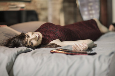 Lächelnde Frau im Abendkleid auf dem Bett, lizenzfreies Stockfoto