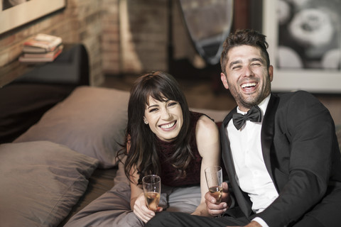 Glückliches Paar in eleganter Kleidung trinkt Champagner im Bett, lizenzfreies Stockfoto