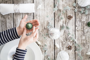 Mädchenhände halten Teelicht vor einem gedeckten Tisch zur Weihnachtszeit - LVF004532