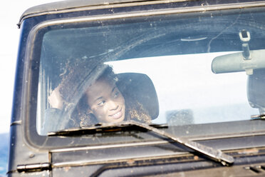 Spanien, Teneriffa, lächelnde Frau sitzt im Auto und beobachtet etwas - SIPF000180