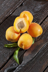 Whole and sliced apricots and an old knife on wood - CSF027122