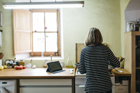 Rückansicht einer Frau beim Kochen auf dem Gasherd in ihrer Küche, lizenzfreies Stockfoto