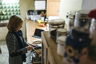 Frau kocht auf einem Gasherd in ihrer Küche - JRFF000429