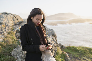 Spain, Ferrol, portrait of smiling woman looking at her smartphone - RAEF000874