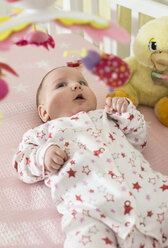 Baby girl lying in a baby cot looking at mobile - DEGF000637
