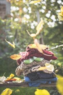Stapel mit warmer Kleidung und fallendes Herbstlaub - DEGF000644