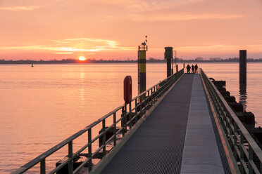 Deutschland, Bremerhaven, Silhouetten von drei Personen, die auf einem Steg stehen und den Sonnenuntergang beobachten - SJF000165