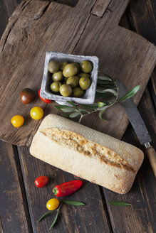 Ciabatta-Brot mit grünen Oliven in Schale, Tomaten und Mini-Paprika auf Holz - CSF027164